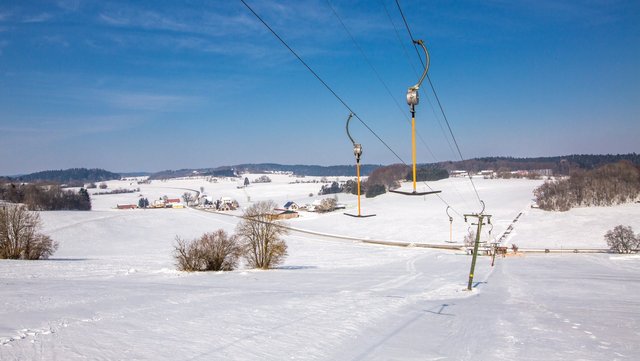 Skilift bei Nusplingen auf schneebedeckten Hügeln und blauem Himmel